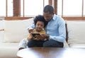 Portrait of happy African American father and son using a tablet while sofa sitting on sofa at home. Having great time together. Royalty Free Stock Photo