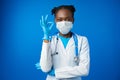 Portrait happy African American female doctor showing ok sign in blue studio Royalty Free Stock Photo