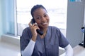 Portrait of happy african american female doctor talking on phone in hospital reception Royalty Free Stock Photo