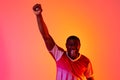 Portrait of happy african american male soccer player raising hand over neon pink lighting