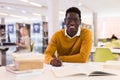 Portrait of happy african-american male student working with book in public library Royalty Free Stock Photo