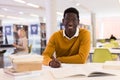 Portrait of happy african-american male student working with book in public library Royalty Free Stock Photo