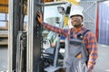 Portrait of a happy African American male worker driving forklift at workplace Royalty Free Stock Photo