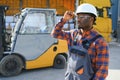 Portrait of a happy African American male worker driving forklift at workplace Royalty Free Stock Photo