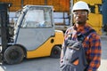 Portrait of a happy African American male worker driving forklift at workplace Royalty Free Stock Photo