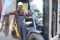 Portrait of a happy African American male worker driving forklift at workplace Royalty Free Stock Photo