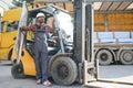 Portrait of a happy African American male worker driving forklift at workplace Royalty Free Stock Photo