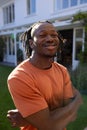 Portrait of happy african american man with dreadlocks outside house smiling in sunny garden Royalty Free Stock Photo