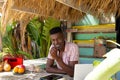 Portrait of happy african american man with laptop behind counter of surf hire beach shack Royalty Free Stock Photo