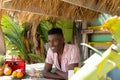 Portrait of happy african american man leaning on counter of surf hire beach shack Royalty Free Stock Photo