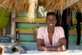 Portrait of happy african american man sitting behind counter of surf hire beach shack Royalty Free Stock Photo