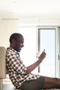 Portrait happy african american man sitting on floor with cellphone Royalty Free Stock Photo