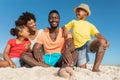 Portrait of happy african american parents and children on sand at beach against blue sky Royalty Free Stock Photo