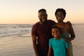 Portrait of happy african american parents with son standing at beach against sky during sunset Royalty Free Stock Photo