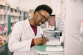 Portrait of a happy African American pharmacist writing prescription at workplace in modern pharmacy Royalty Free Stock Photo