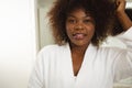 Portrait of happy african american woman in bathroom wearing bathrobe, looking to camera and smiling Royalty Free Stock Photo