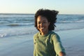 Portrait of happy african american woman looking at camera and smiling on beach at sundown Royalty Free Stock Photo