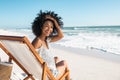 Happy smiling young woman sitting on deck chair at beach during summer vacation Royalty Free Stock Photo