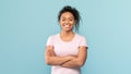 Portrait of happy african american woman standing with folded arms, looking and smiling at camera, blue background Royalty Free Stock Photo