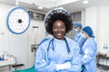 Portrait of happy African American woman surgeon standing in operating room, ready to work on a patient. Female medical worker in Royalty Free Stock Photo