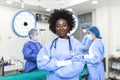 Portrait of happy African American woman surgeon standing in operating room, ready to work on a patient. Female medical worker Royalty Free Stock Photo