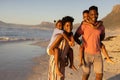 Portrait of happy african american young parents piggybacking son and daughter at beach against sky Royalty Free Stock Photo