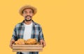 Portrait of happy African farmer man standing holding a crate of fresh cacao fruit with isolated on yellow background Royalty Free Stock Photo