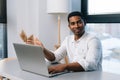 Portrait of happy African male entrepreneur using laptop computer and friendly looking at camera while enjoying work Royalty Free Stock Photo