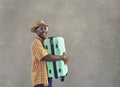 Portrait of happy African man in sunglasses and sun hat holding mint green suitcase Royalty Free Stock Photo