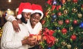 Portrait of happy afro couple holding gift and standing near Christmas tree Royalty Free Stock Photo