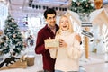 Portrait of happy amazed young woman receiving gift box from loving boyfriend standing in hall of celebrate shopping Royalty Free Stock Photo