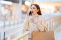 Portrait of happy amazedyoung woman with open mouth holding shopping paper bags and talking using mobile phone, Royalty Free Stock Photo