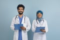 Portrait of happy arab male and female doctors in uniform holding clipboards Royalty Free Stock Photo