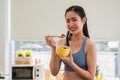 Beautiful Asian young female eating strawberry yogurt for health in the kitchen room at the apartment Royalty Free Stock Photo