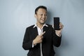 A portrait of a happy Asian businessman is smiling and holding his smartphone showing copy space on it`s screen wearing black sui Royalty Free Stock Photo