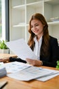 A portrait of a happy Asian businesswoman is examining financial reports at her desk Royalty Free Stock Photo
