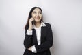 A portrait of a happy Asian businesswoman is smiling while talking on phone call wearing a black suit isolated by a white Royalty Free Stock Photo