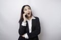 A portrait of a happy Asian businesswoman is smiling while talking on phone call wearing a black suit isolated by a white Royalty Free Stock Photo