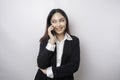 A portrait of a happy Asian businesswoman is smiling while talking on phone call wearing a black suit isolated by a white Royalty Free Stock Photo