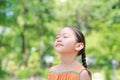 Portrait of happy Asian child close their eyes in garden with Breathe fresh air from nature. Close up kid girl relax in green park