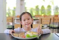 Portrait of happy Asian child girl eating Pork steak and vegetable salad on the table with holding knife and fork. Children having Royalty Free Stock Photo