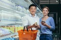 Portrait of a happy asian couple of consumers, supermarket shoppers or grocery store looking at camera smiling. Glad Royalty Free Stock Photo