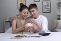 Portrait of a happy Asian couple at home saving money in a piggybank. Woman and man couple at home saving money in a piggybank. Royalty Free Stock Photo