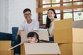 Portrait of happy Asian family moving to new house with cardboard boxes and playing cardboard box. Royalty Free Stock Photo