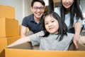 Portrait of happy Asian family moving to new house with cardboard boxes and playing cardboard box. Royalty Free Stock Photo