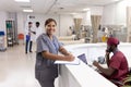 Portrait of happy asian female doctor with clipboard at reception desk of hospital ward Royalty Free Stock Photo