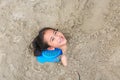 Portrait of happy asian little child girl buried in the sand at the beach. Close up kid playing with sand Royalty Free Stock Photo