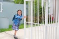 Portrait of happy asian little kid girl in school uniform trying push and pull door fence of house to close or open before leave