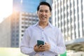 Portrait happy asian man holding smart phone and looking at camera with smile face in cityscape background Handsome confident Royalty Free Stock Photo