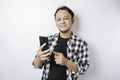 A portrait of a happy Asian man is smiling while holding on his phone, isolated by white background Royalty Free Stock Photo